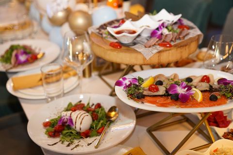 Burrata salad with cherry tomatoes and arugula next to a smoked fish platter on a banquet table