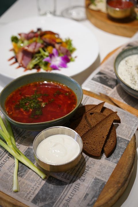 Bowl of borscht with sour cream, rye bread and green onions
